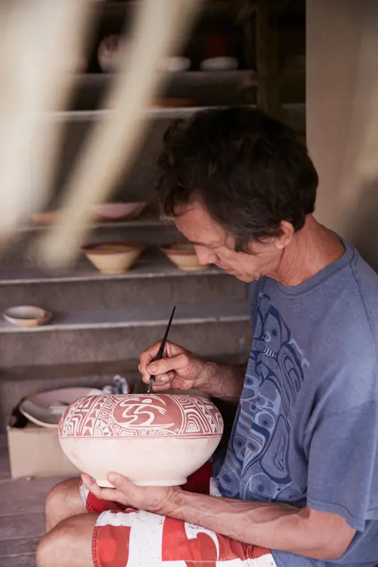 Peter Owen en train de peindre une poterie polynésienne