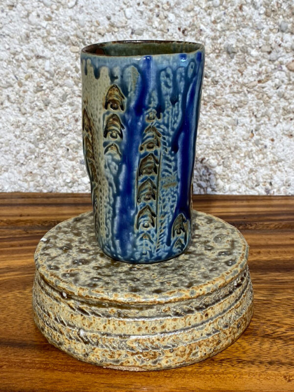 This tall porcelain glass is decorated with Polynesian designs and Japanese clay relief