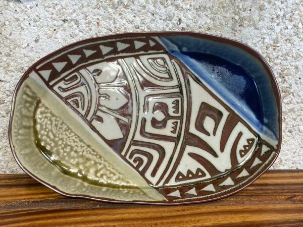 Medium size porcelain oval platter with brown carved Polynesian designes surrounded with beautiful Huahine blue and green glazes. This piece has a very local feeling.
